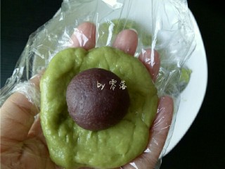 13、自制青团,戴上一次性手套(没有手套,也可裹保鲜膜),在上面抹点猪油(或玉米油),取一小块面团,揉圆,压扁,包上豆沙馅儿;