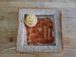 14、苹果玫瑰花土司,将卷好的苹果玫瑰花摆在土司框中。