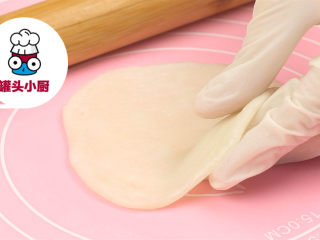 3、网红Q香橘子大福,戴上防粘手套，沾些熟糯米粉，取一小块面团，搓圆压扁，再擀平成圆形，依次擀好全部