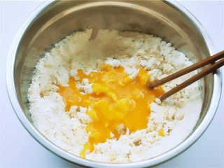3、花瓣馒头,把加有酵母粉的南瓜糊分次加入面粉中间,不要碰到盆边,用筷子沿着盆边搅拌