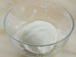 3、烫面豆沙饼,再用手揉成光滑的软面团，盖湿布或保鲜膜静置三十分钟左右，冬季气温低可适当延长时间
