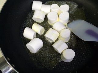 5、牛轧糖夹心苏打饼干,加入棉花糖，用刮刀按压、搅拌，直到棉花糖融化。