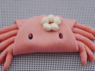 13、花样小螃蟹馒头,把白色面团揉成小圆球，用清水把小面团粘在一起，形成一个花朵图案。