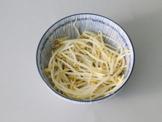 4、水煮肉片,将焯烫后的豆芽铺在碗里。