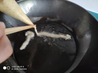 13、茴香小油条（不用手揉）,炸锅油热后，将裱花袋里的面糊挤入油锅，一根小油条就出来了。觉得长度够了就用筷子夹住开口。或者用手按住开口都行。
