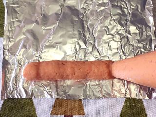 4、自制宝宝牛肉肠,准备锡箔纸剪成合适大小，在裱花袋上剪个口子，挤上牛肉泥。