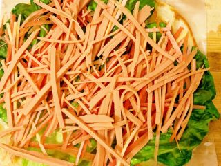 11、香酥黑椒手抓饼,放完胡萝卜????丝将切好的备用火腿丝放置上面。