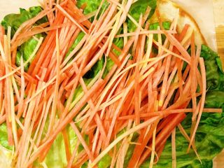 10、香酥黑椒手抓饼,依次将胡萝卜????丝放至生菜叶上。