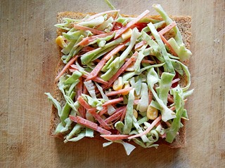 7、沼三明治,在涂抹好番茄酱的吐司片上均匀铺上一层卷心菜沙拉。