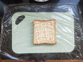 6、金枪鱼沙拉三明治,取一片吐司,我买的是全麦吐司,(底下铺上保鲜膜,)挤上沙拉酱。