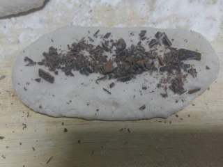 3、黑米面巧克力馒头圈,分成若干份，取一个，擀成长圆行，把巧克力碎放在上面，