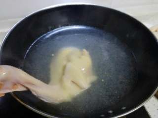 2、白切鸡,半锅水烧开后,用手捏住鸡头,将鸡身放入开水中浸汤,每隔几秒钟将鸡提出,这个过程反复几次,可以让鸡表面定型也可以保持鸡肉鲜嫩。