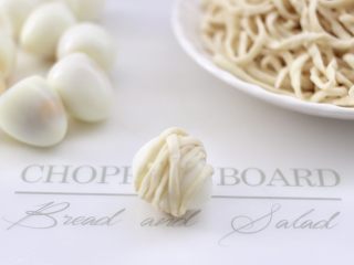 5、香辣孜然之～腰缠万贯,取一个鹌鹑蛋，先把一根手擀面条一圈一圈缠绕上去。