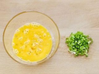 2、培根鸡蛋饼,将鸡蛋磕入容器中充分搅打均匀，小香葱洗净切葱花备用。