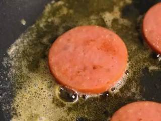 3、5分钟快手早餐，营养的吐司三明治,平底锅开小火煎化黄油，再放入香肠两面煎香