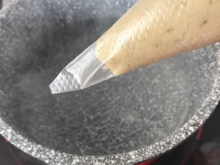 10、虾滑条,水烧至微微沸腾，裱花袋剪个口子，挤入锅内，这是口子比较细的，挤出的是细长条的，比较适合小月龄宝宝。也可以剪口子大一点，挤出一小段，用勺子挖出入锅