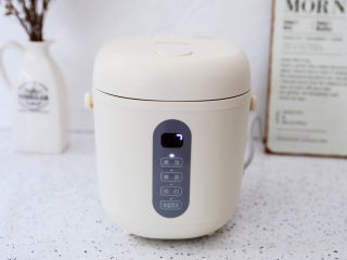 2、午餐肉饭团,首先先煮饭,将大米淘洗干净,放入电饭煲内胆中,加入适量的清水,盖上锅盖,启动煮饭功能,我用的是三食黄小厨迷你电饭煲,它小巧玲珑,不占空间,0.8L小容量,适合1-2人食,再也不怕煮多浪费了,还有24小时预约功能,只要睡前将食材放入饭煲,睡前预约,第二天早上就可以吃到。