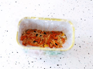 14、午餐肉饭团,午餐肉的盒子,铺上一套保鲜膜,再把米饭填入盒子的四分之一,压实