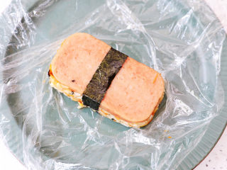 16、午餐肉饭团,最后将保鲜膜提出,取出饭团,再包上一条海苔即可