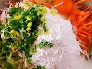 6、土豆胡萝卜抱蛋,放入葱花、香菜、面粉、打入一个鸡蛋、盐、味精、半勺油、少许清水