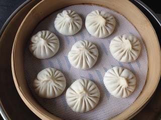 15、灌汤包,笼屉里放入不粘垫（如果没有，可以在包子的底部放一个玉米叶或油纸等防粘材料），把包子放在上面，水开后放进蒸锅，盖上盖子中大火蒸制8分钟即可