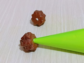 18、巧克力奶油泡芙,这时泡芙也凉了,用筷子捅个小洞洞,再将裱花嘴插入洞洞里,挤入奶油即可。
