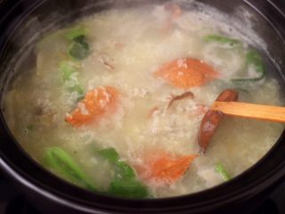 15、螃蟹青菜辣椒粥,大火煮沸后,加入洗净的青菜,煮至青菜断生变色的时候。