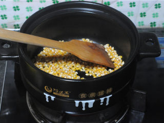 3、砂锅爆米花,随着温度不停上升,用木质的铲子不停地搅拌,让玉米均匀受热