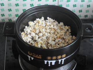 5、砂锅爆米花,用锅盖稍微挡着点,防止玉米爆出来,继续快速划圈搅拌玉米,这时候,爆裂的玉米越来越多