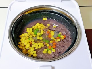 11、黑米红豆粥,煮粥30分钟时米已经软糯啦！加入时蔬玉米片，煮20分钟，最后提前5分钟加入腌制好的虾仁，待饭煲滴的一声，会自动进入保温状态，这时就可以断电啦。