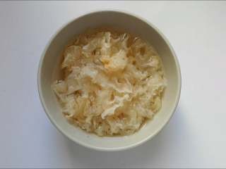 2、银耳莲子羹,银耳浸泡在清水里，变软后去根撕成小朵。多次搓揉换水，洗去表面杂质