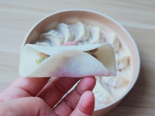 8、猪肉芹菜蒸饺,饺子皮半圈沾一点点水，有利于粘合。饺子馅放一点，先把饺子皮中间捏一下。