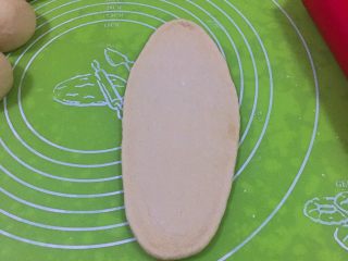 15、奶酪火腿肉松面包,将剂子擀成椭圆形。