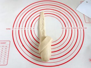 12、牛奶炼乳蔓越莓软欧,没擀开的部分用手掌轻轻压下，将切开的右边那条面片往左下角方向折。