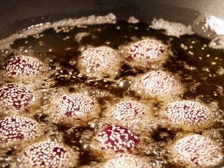 14、紫薯糯米丸子,等到丸子漂浮起来以后再转中火炸丸子。炸到丸子表壳变硬即可捞出控油。