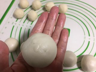 11、酥皮点心紫薯酥,把一个油皮捏成圆片放进一个油酥,用右手的虎口慢慢朝上推包住油酥。