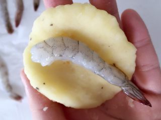 6、鲜虾可乐饼,取一团薯泥,先用手握成扁扁的圆饼状,中间用手指压一道浅浅的小沟,把虾放进去。