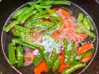 5、荷塘小炒,锅里放入一大碗开水,放入一勺盐,一勺油,少许白糖调匀,把荷兰豆,胡萝卜,藕片放入焯烫30秒,焯好捞出来用冷水冲凉待用。