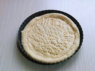 5、罗勒意式披萨,取一款面团用擀面杖擀圆饼，与自己的披萨盘一样大小即可，再用食品叉子叉满洞洞眼，如图。