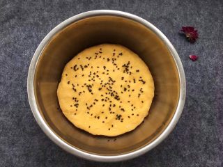 11、南瓜发糕,撒上黑芝麻，盖上保鲜膜，让其静静发酵。（盆底刷油，目的是为了南瓜发糕容易脱模）