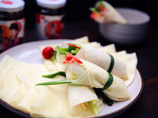 16、春饼,蔬菜用调料拌好,包入春饼皮里,用小葱捆住。