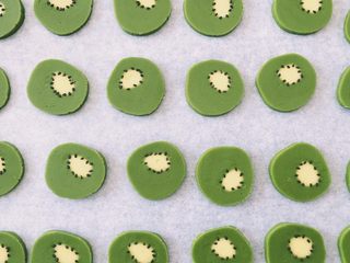 12、抹茶猕猴桃小饼干,用少量黑芝麻装饰，技巧是一手拿牙签蘸水再粘黑芝麻，另一只手也拿着牙签做辅助，把黑芝麻摆放好。考验耐心的时刻哦～