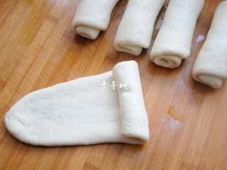 12、老字号甜咸味椒盐油酥金丝饼,把面团压扁,用擀面杖从中间向两头擀开成椭圆状,再从一头卷起来,卷到另外一头压紧。