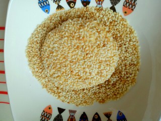 8、芝麻南瓜饼,包好的南瓜饼放入熟芝麻的容器里，沾满芝麻，依次做完。