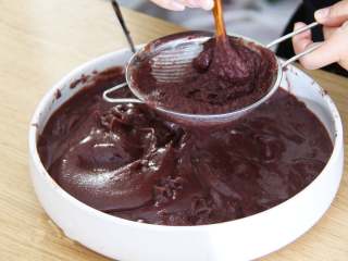 4、自制红豆沙,用料理机打碎红豆沙,取一个过滤网,用小勺过滤豆沙,过滤的渣子不要,下面出来的就非常细腻了。