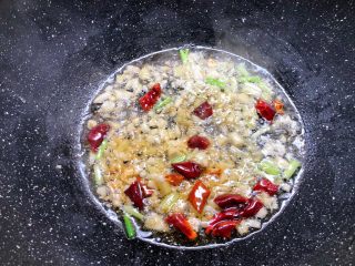 4、黄焖鸡,锅里放入适量油烧热,把冰糖放入小火炒出糖色,再把干辣椒,葱白,姜末,蒜末放入炒出香味。