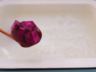 7、紫薯百合核桃糯米粥,大火煮沸后用勺子撇去沙锅里的浮末，再加入用刀切块的紫薯。