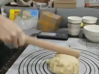5、菠萝面包,用擀面杖不停的敲打,像搓衣服一样不停来回搓,这样的步骤需要15分钟左右,才能揉成不黏手的面团