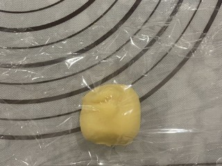 14、菠萝面包,酥皮两面用保鲜膜包裹后,按压,用擀面杖压成圆形