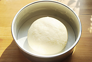 4、超级流行的爆款面包【奶酪包】 ,取出发酵好的面团，轻轻用手掌按压排气，然后再次整圆，放入抹了黄油的八寸圆模中；